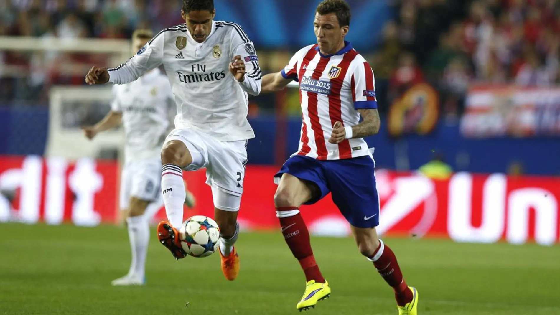 El delantero croata del Atlético de Madrid Mario Mandzukic (d) lucha el balón con el francés Raphael Varane, del Real Madrid