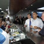 Barack Obama, junto al goberndor de Illinois, Pat Quinn (dereccha), y al candidato demócrata al Senado, Alexi Giannoulias, saludan a la cocinera de una cafeteria en un alto para desayunar en Chicago