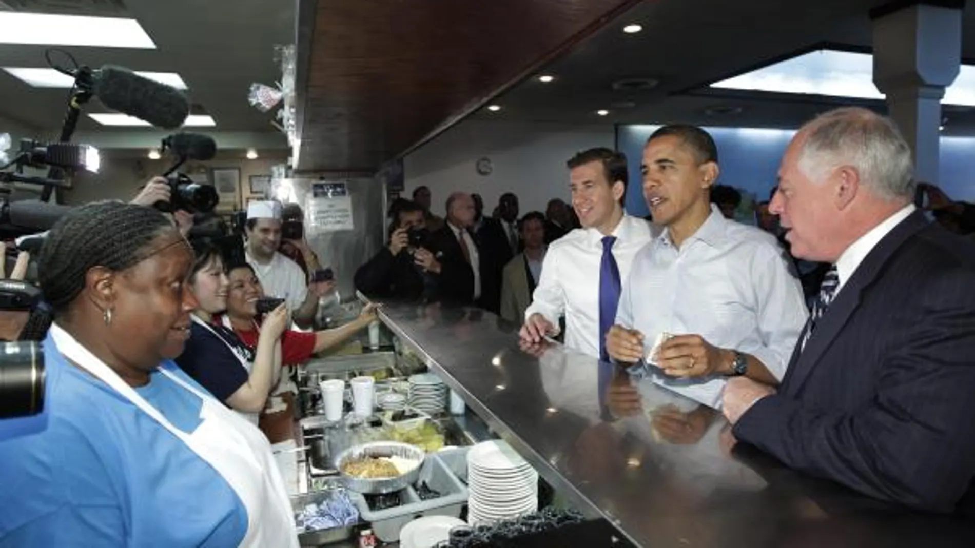 Barack Obama, junto al goberndor de Illinois, Pat Quinn (dereccha), y al candidato demócrata al Senado, Alexi Giannoulias, saludan a la cocinera de una cafeteria en un alto para desayunar en Chicago