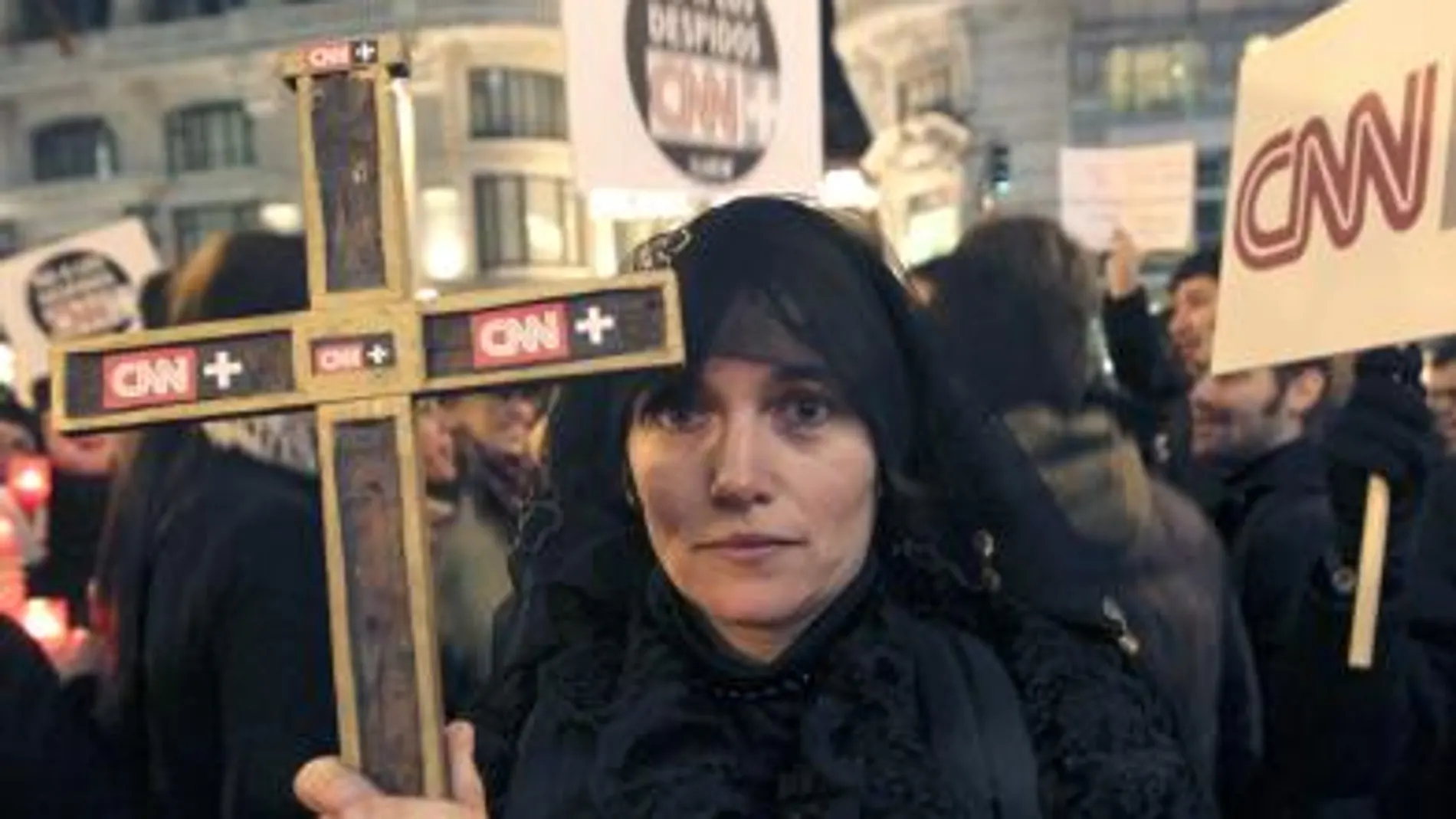 Una mujer vestida de negro porta una cruz durante la concentración en contra del cierre de CNN+ esta tarde en Madrid. Tras once años en antena y con una audiencia minoritaria pero fiel, CNN +