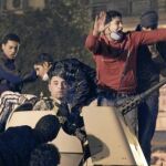 Varios manifestantes toman el control de un blindado del ejército durante las manifestaciones de ayer en El Cairo, en las que murieron varias personas