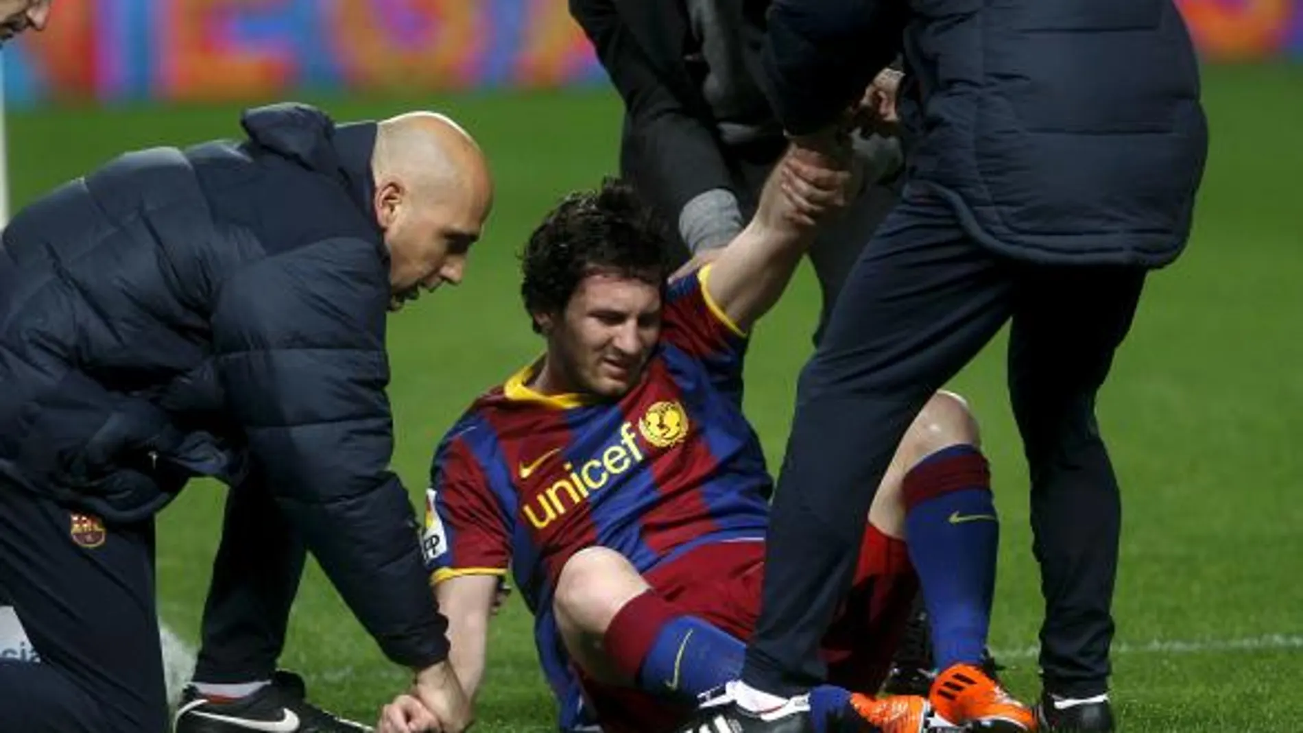 El delantero argentino del FC Barcelona Lionel Messi (c) recibe asistencia médica tras chocar con el portero del Sevilla CF Javi Varas