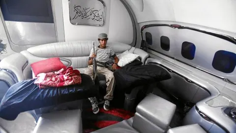Un rebelde se acomoda en uno de los sofás del avión privado de Muamar Gadafi, ayer, en Trípoli