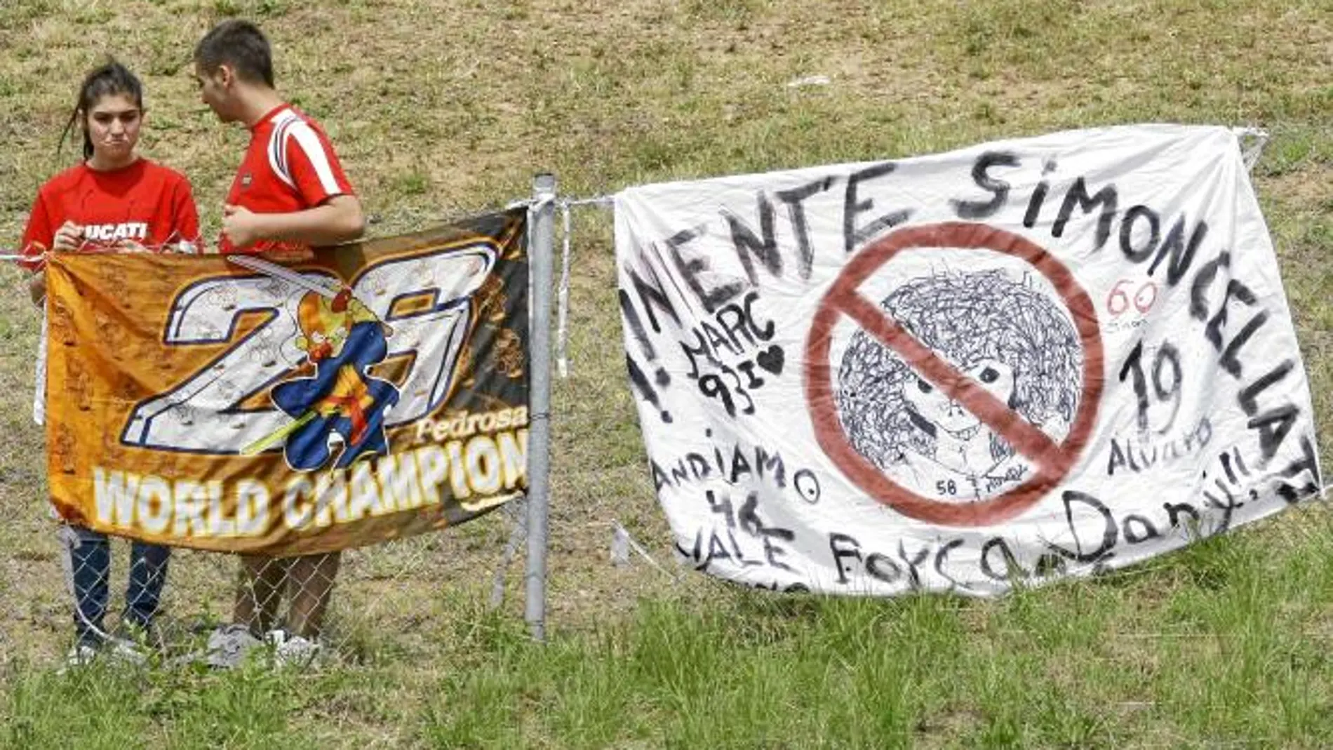 Dos espectadores colocan una pancarta a favor de Pedrosa y otra en contra de Marco Simoncelli ayer en el circuito de Montmeló