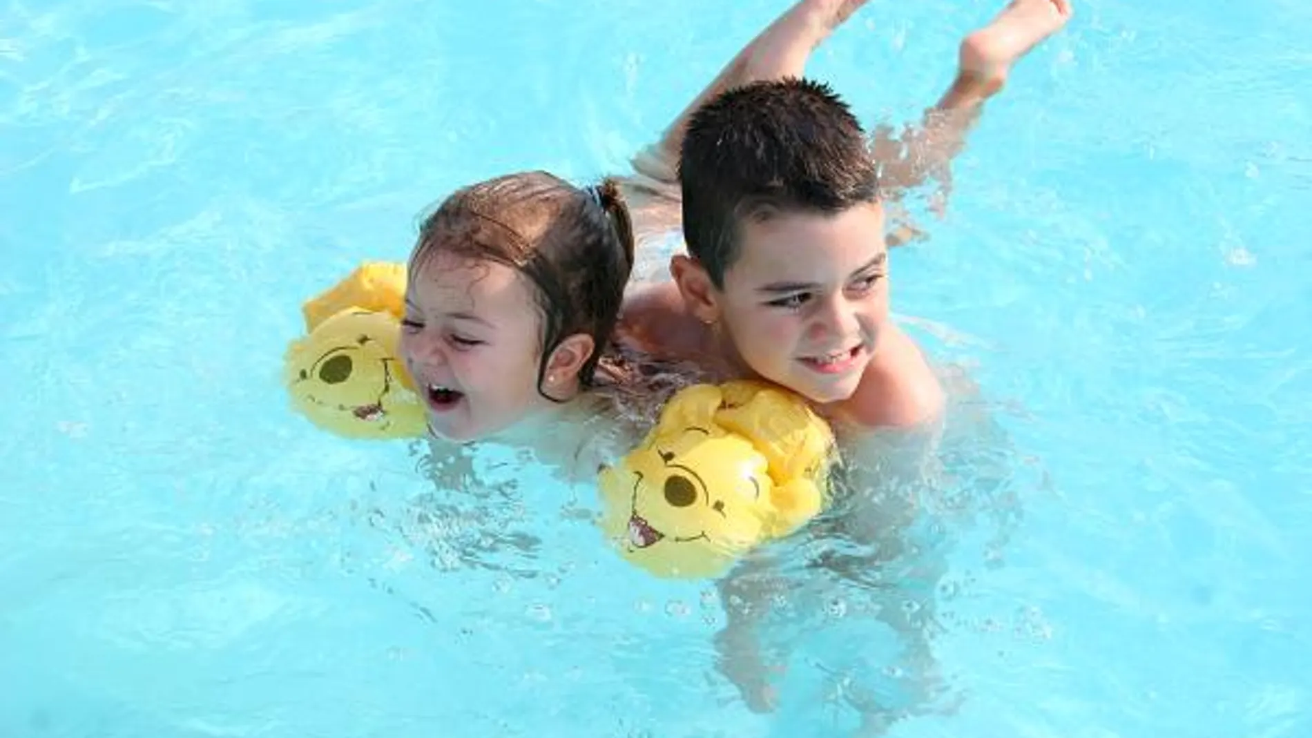 Dos niños bañándose en una piscina