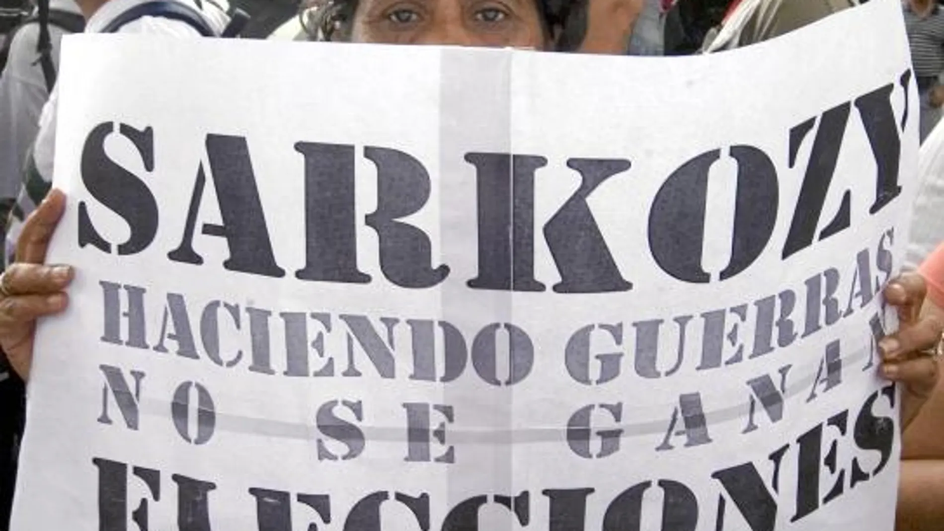 Una manifestante en Venezuela sujeta una pancarta contra el presidente francés, Nicolas Sarkozy
