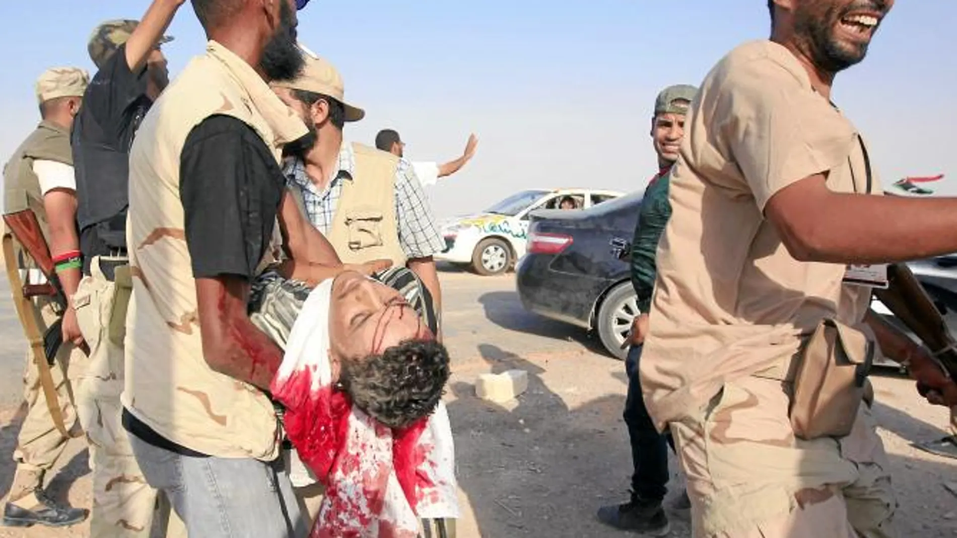 Milicianos rebeldes transportan a retaguardia a un compañero herido durante la batalla por Sirte, donde resistían los gadafistas