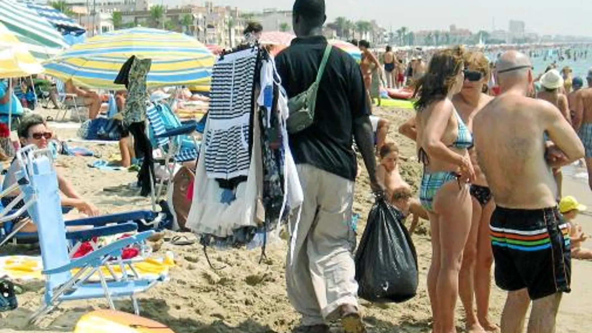 En la imagen, un joven mantero intenta vender todo tipo de productos a los usuarios de una playa de Calafell, durante este verano, lejos de las áreas para el top manta