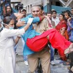 Un agente de seguridad ayuda a una herida tras la explosión en Nueva Delhi
