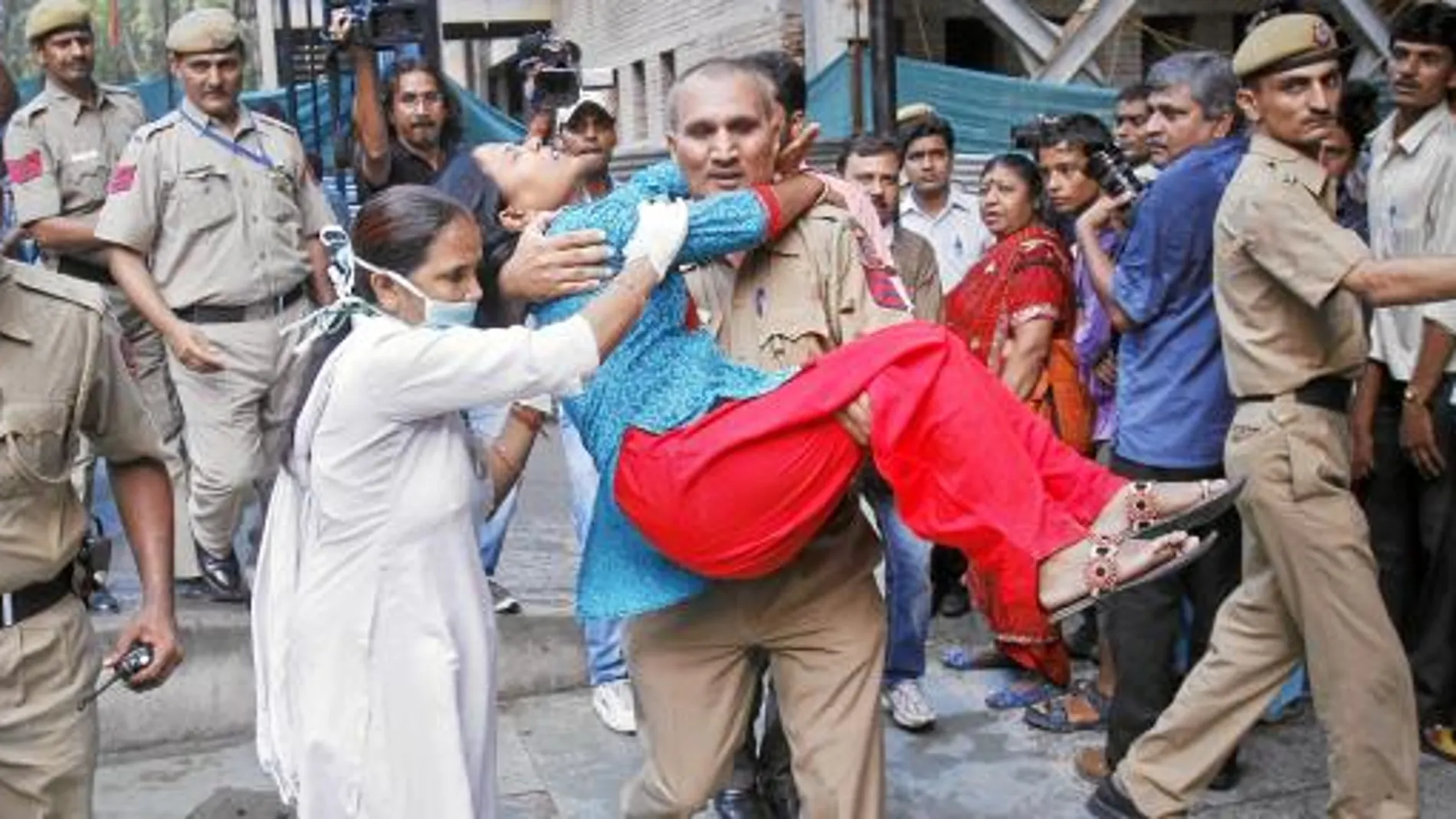 Un agente de seguridad ayuda a una herida tras la explosión en Nueva Delhi