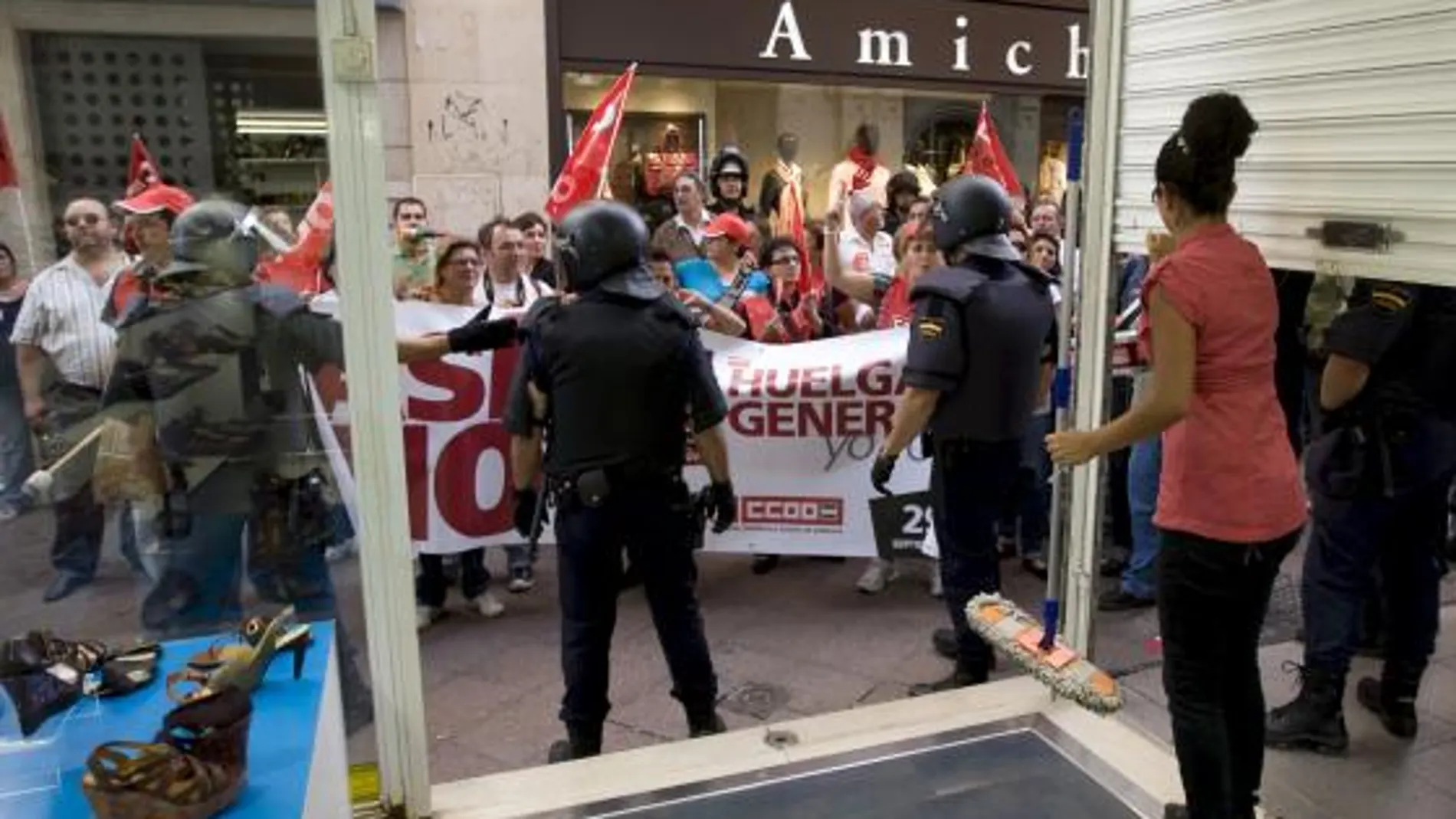 Una empleada de un negocio del centro de Sevilla, echa las persianas ante la presión de un piquete