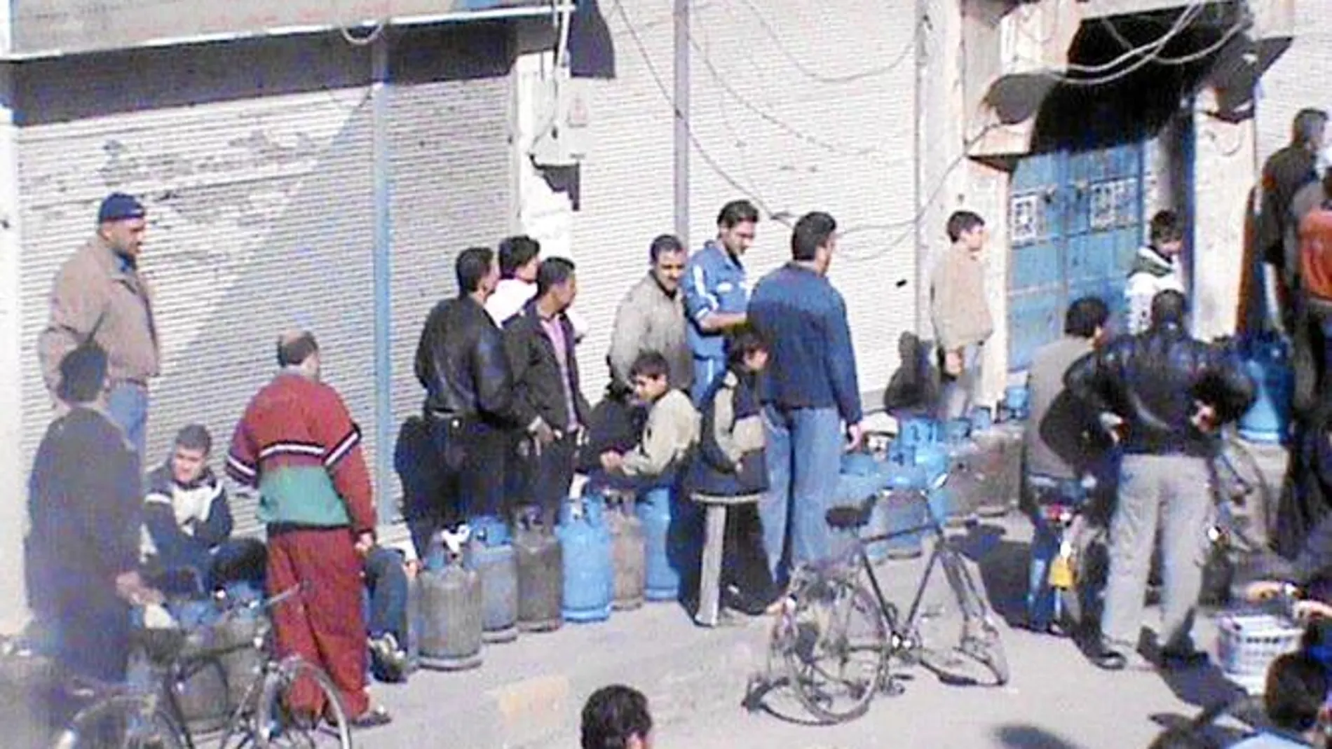 Un grupo de sirios, ayer, hace cola para cambiar bombonas de gas en un puesto callejero en la ciudad de Homs