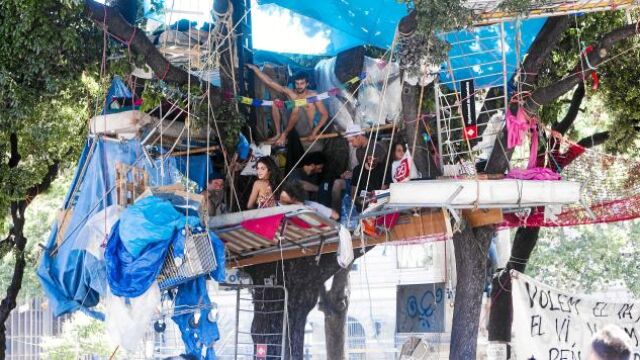 En la foto de la izquierda, un grupo de indignados permanece en su «campamento» en el que incluso se han construido cabañas en los árboles. Abajo, miembros de la limpieza iniciaron ayer sus labores de desalojo.