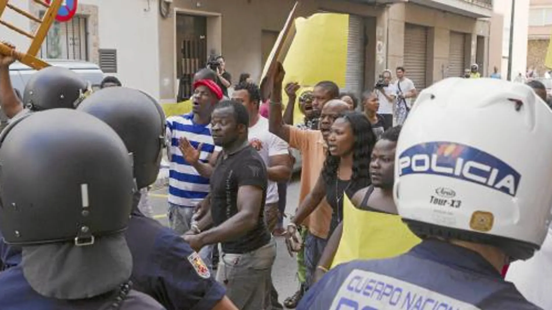 Un retén policial vigila a los manifestantes nigerianos que ayer protestaron por la muerte de su compatriota
