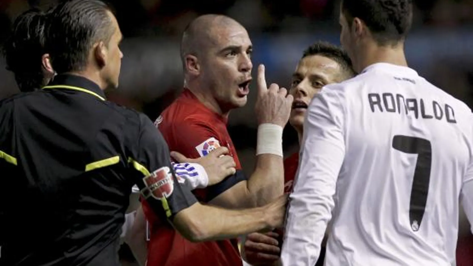 El delantero portugués del Real Madrid Crsitiano Ronaldo (d) se encara con los jugadores del Osasuna el uruguayo Walter Pandiani (c) y Javier Camuñas (2d) en presencia del árbitro, César Muñíz Fernández,