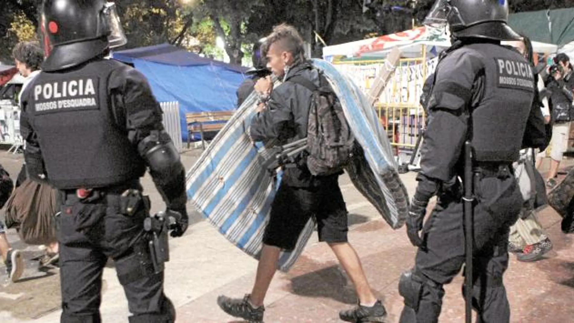 Un «irreductible» recoge sus pertenencias durante el desalojo de ayer de madrugada en plaza Catalunya.
