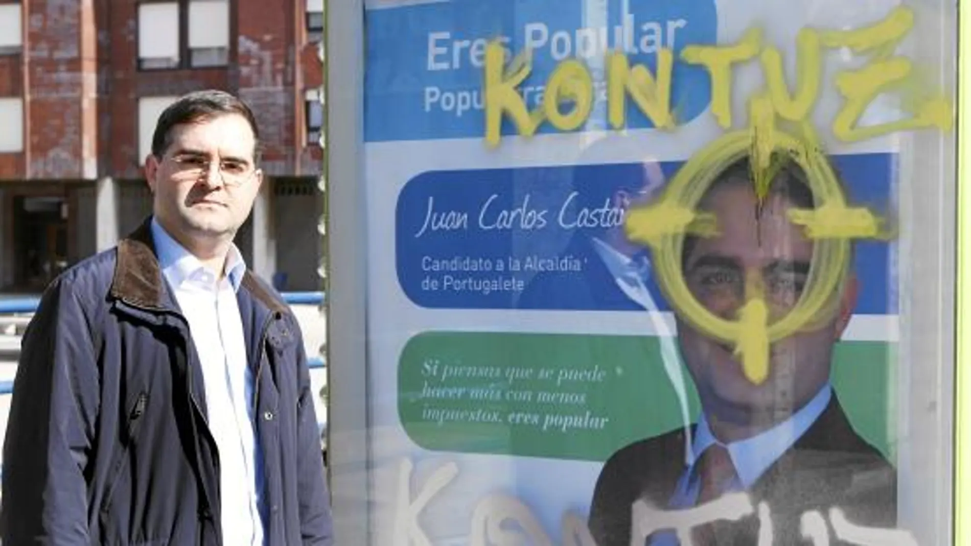 El concejal y candidato del PP a la alcaldía de Portugalete, Vizcaya, al lado de la pintada amenazante