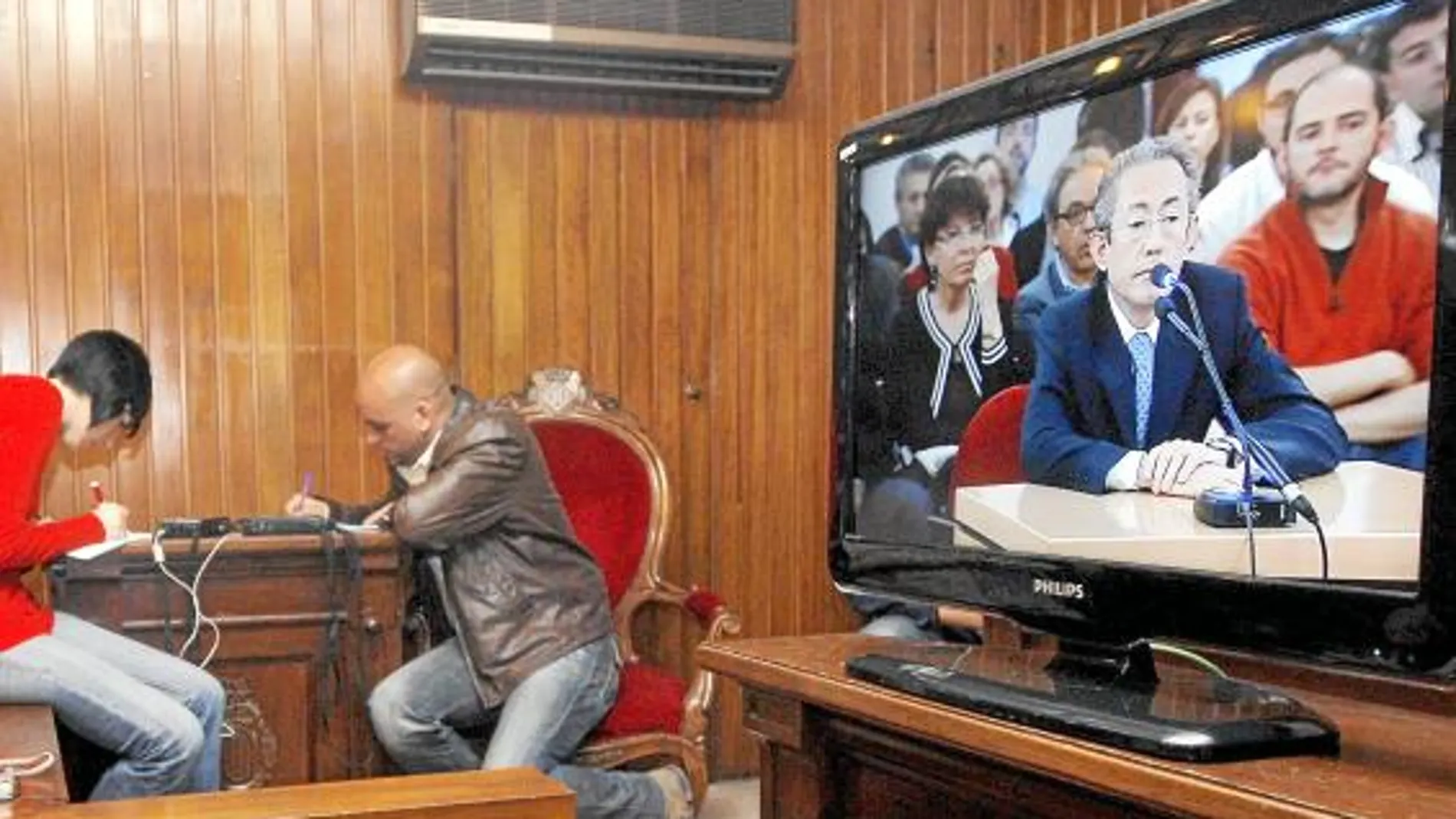 Dos periodistas toman nota mientras siguen la declaración de Ángel Luna en un monitor