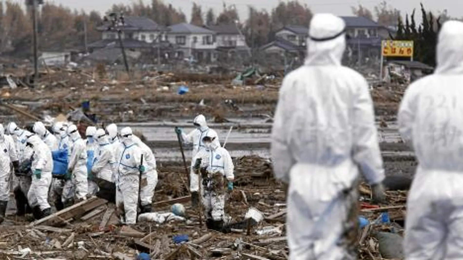 Policías con trajes anticontaminación portan un cadáver hallado, ayer, cerca de Fukushima.