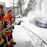 Un grupo de bomberos rocía con espuma un coche durante la jornada de huelga, ayer en Bruselas