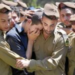 Soldados israelíes consuelan a un familiar del militar asesinado en el ataque del pasado jueves