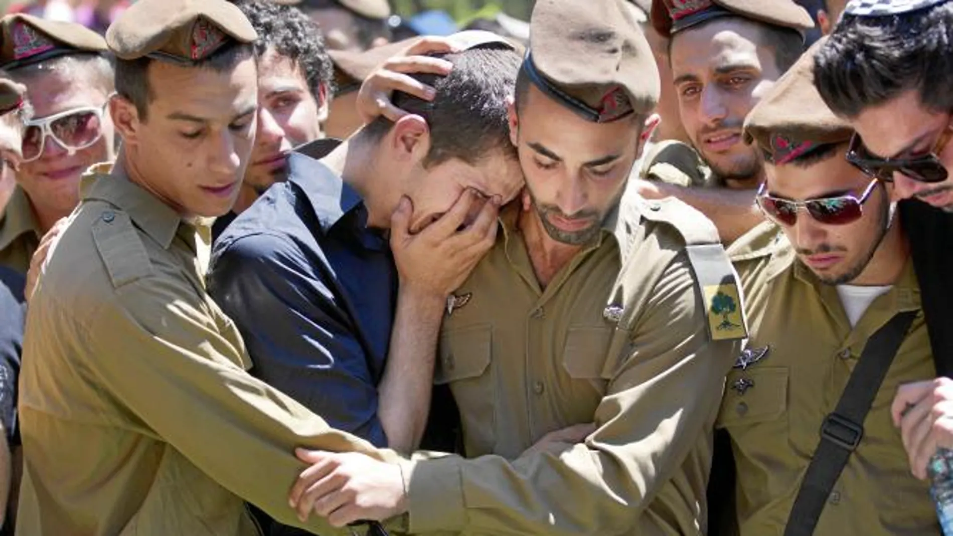 Soldados israelíes consuelan a un familiar del militar asesinado en el ataque del pasado jueves
