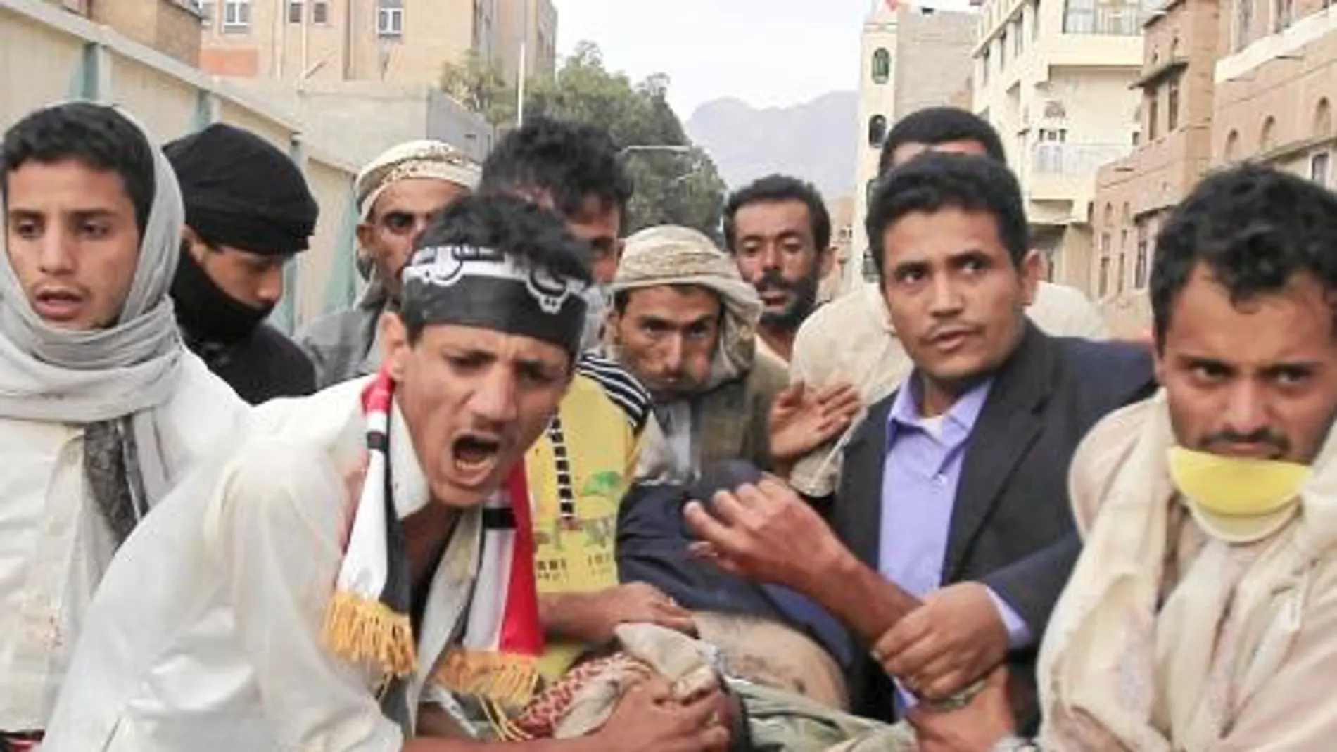 Manifestantes antigubernamentales trasladan a uno de los heridos, ayer, durante las protestas en Saná