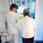 En la imagen, una enfermera atiende a una anciana en un centro especializado
