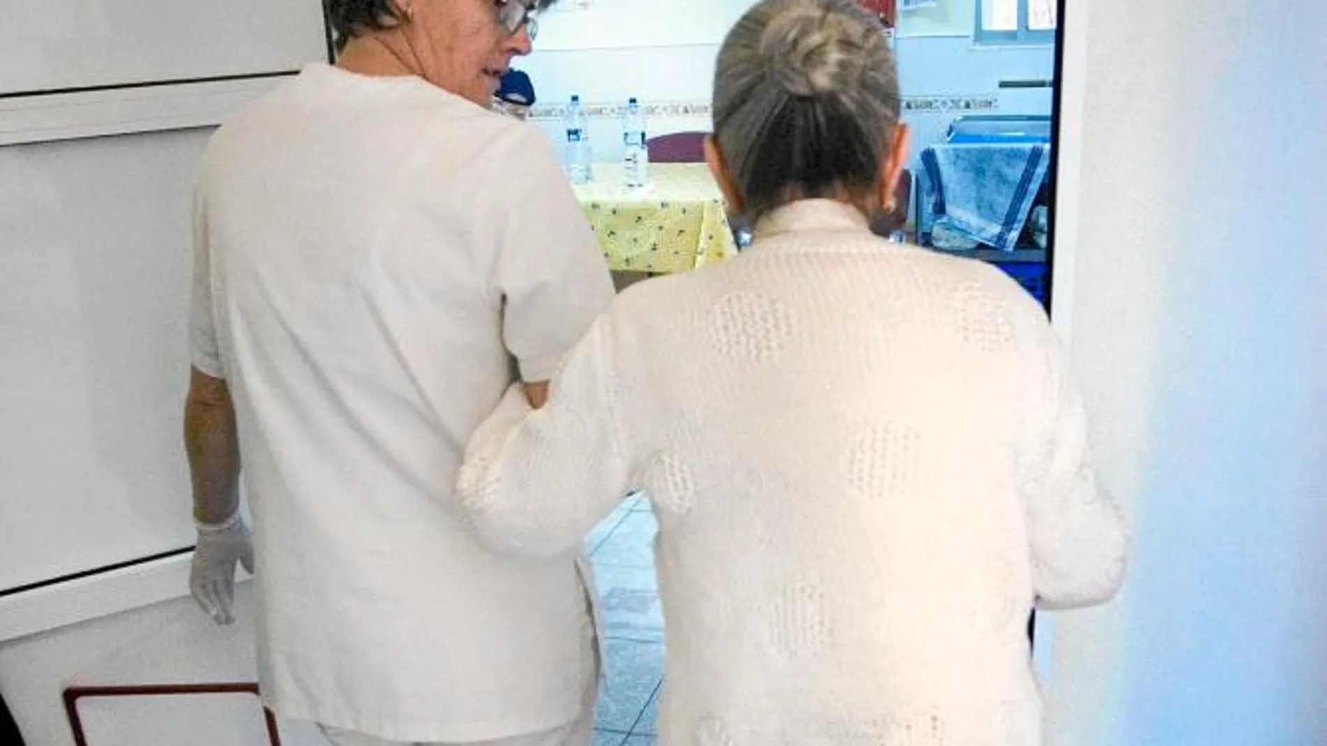 En la imagen, una enfermera atiende a una anciana en un centro especializado