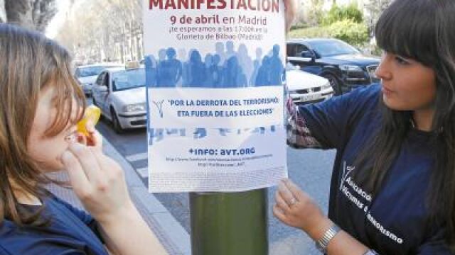 Dos voluntarias con uno de los carteles de la marcha unitaria del 9 de abril «Por la derrota del terrorismo: ETA fuera de las elecciones»