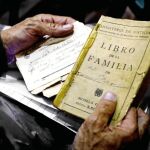 Un hombre sostiene entre sus manos un libro de familia y un acta de defunción del hospital sin sellar
