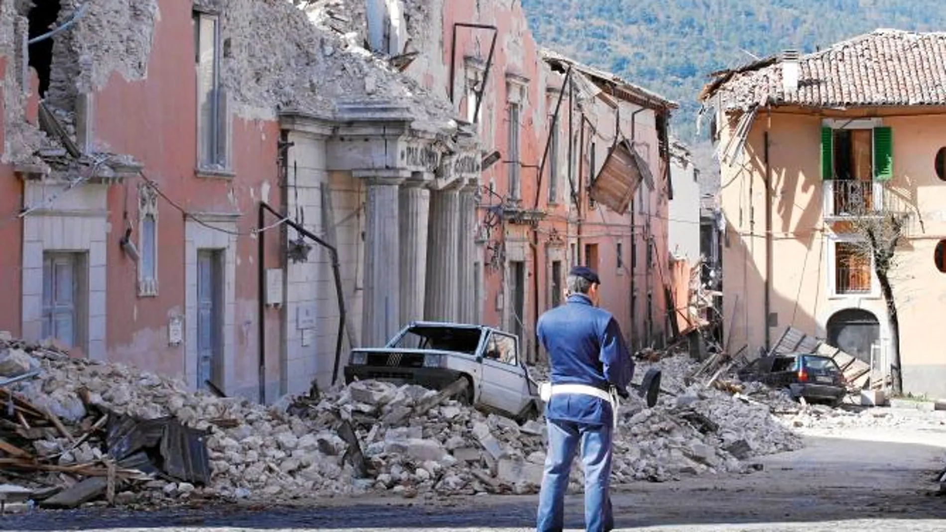 Un policía observa las ruinas de los edificios después del terremoto en L'Aquila en 2009