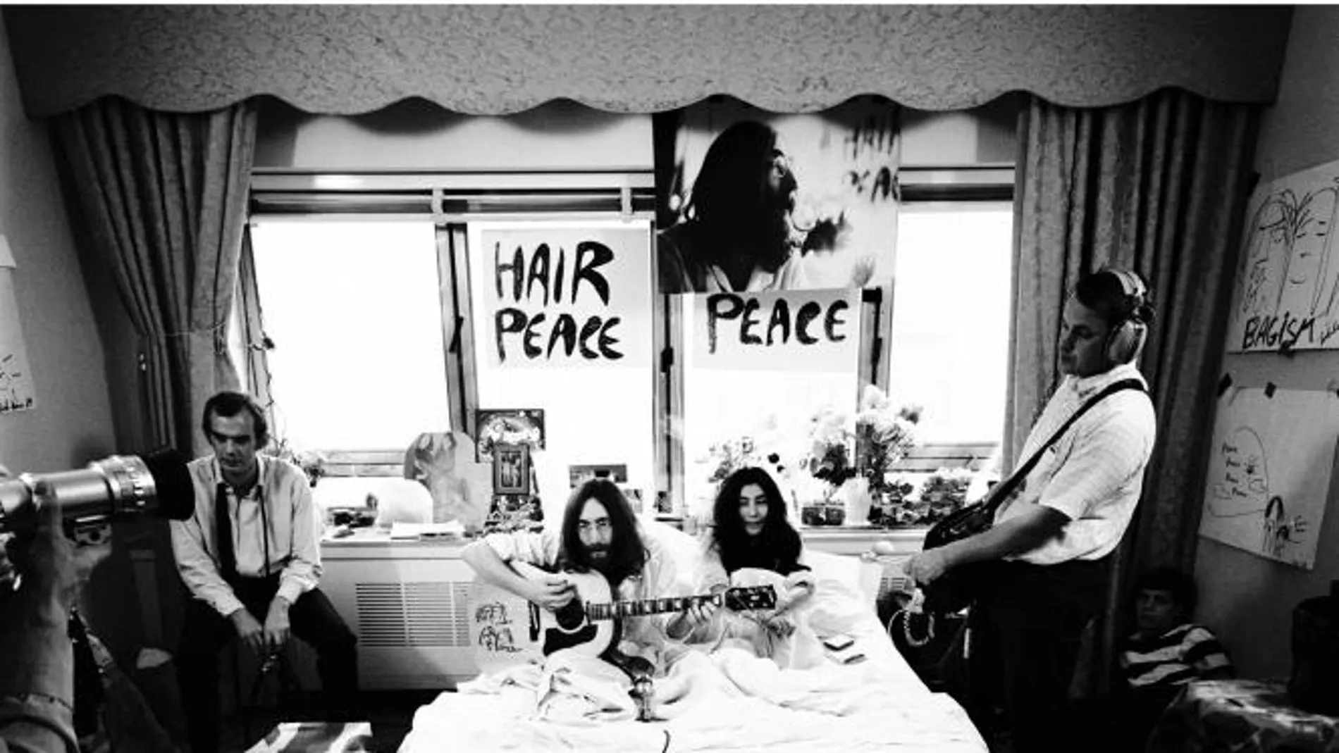 Foto titulada "En la cama" tomada por Gerry Deiter, donde se ve a Yoko Ono y John Lennon tocando la guitarra acústica en pijama en una cama en un hotel de Montreal en 1969, durante su segundo encierro de ocho días por la paz