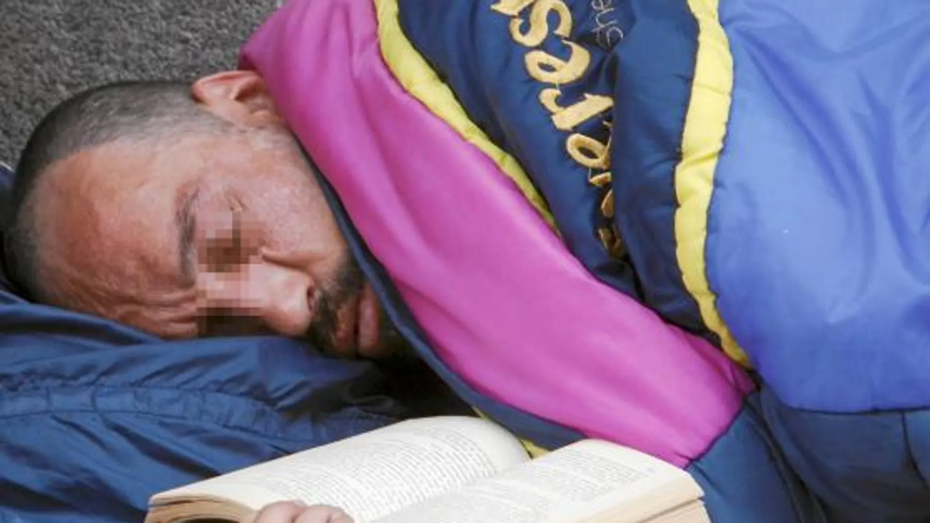 Una persona sin hogar y sin recurso alguno duerme junto a un libro que le acompaña en una esquina de una calle de Valladolid