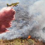 Una avioneta lanza retardante sobre las llamas e escasos metros del término municipal de Chulilla