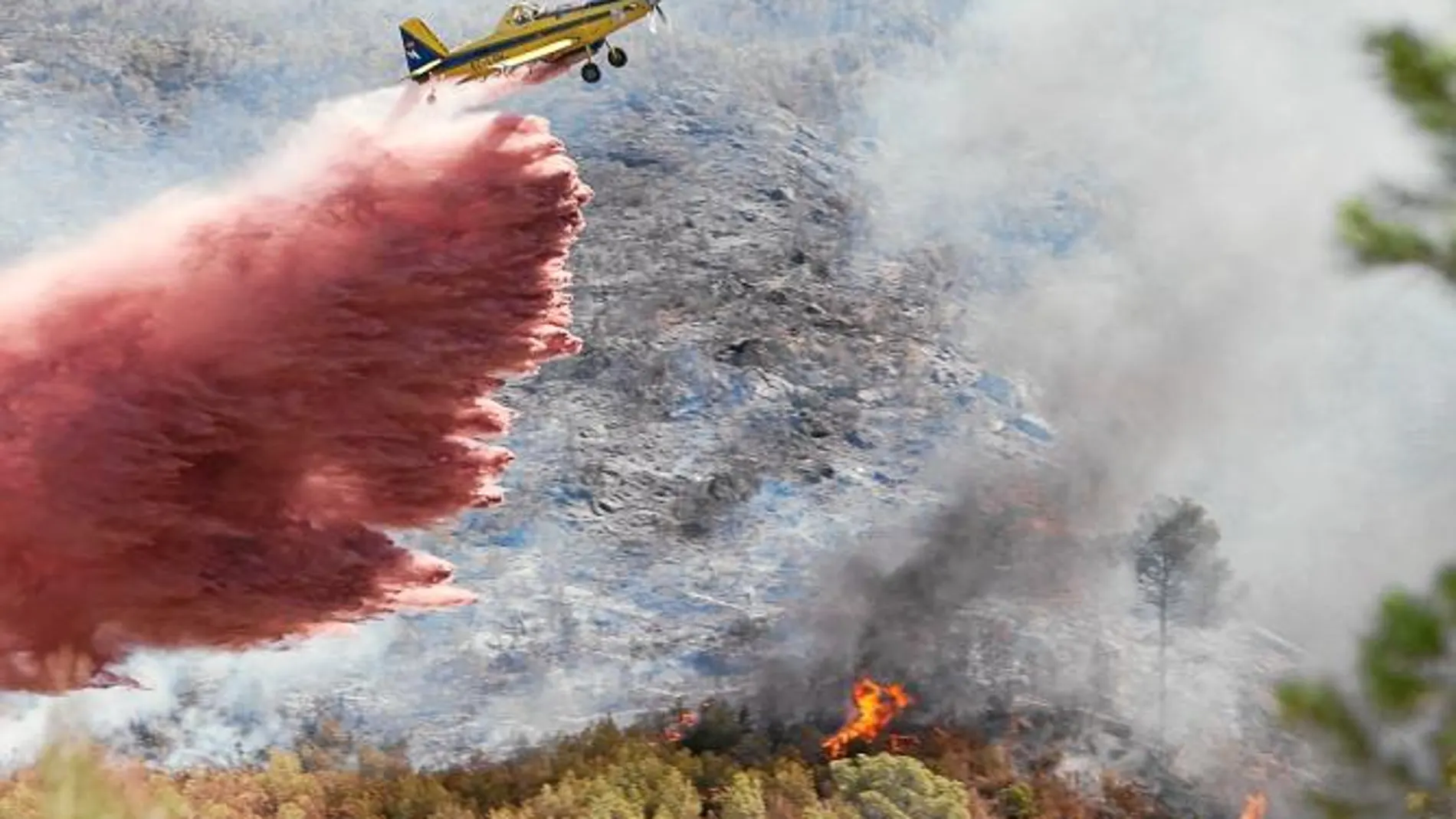 Una avioneta lanza retardante sobre las llamas e escasos metros del término municipal de Chulilla