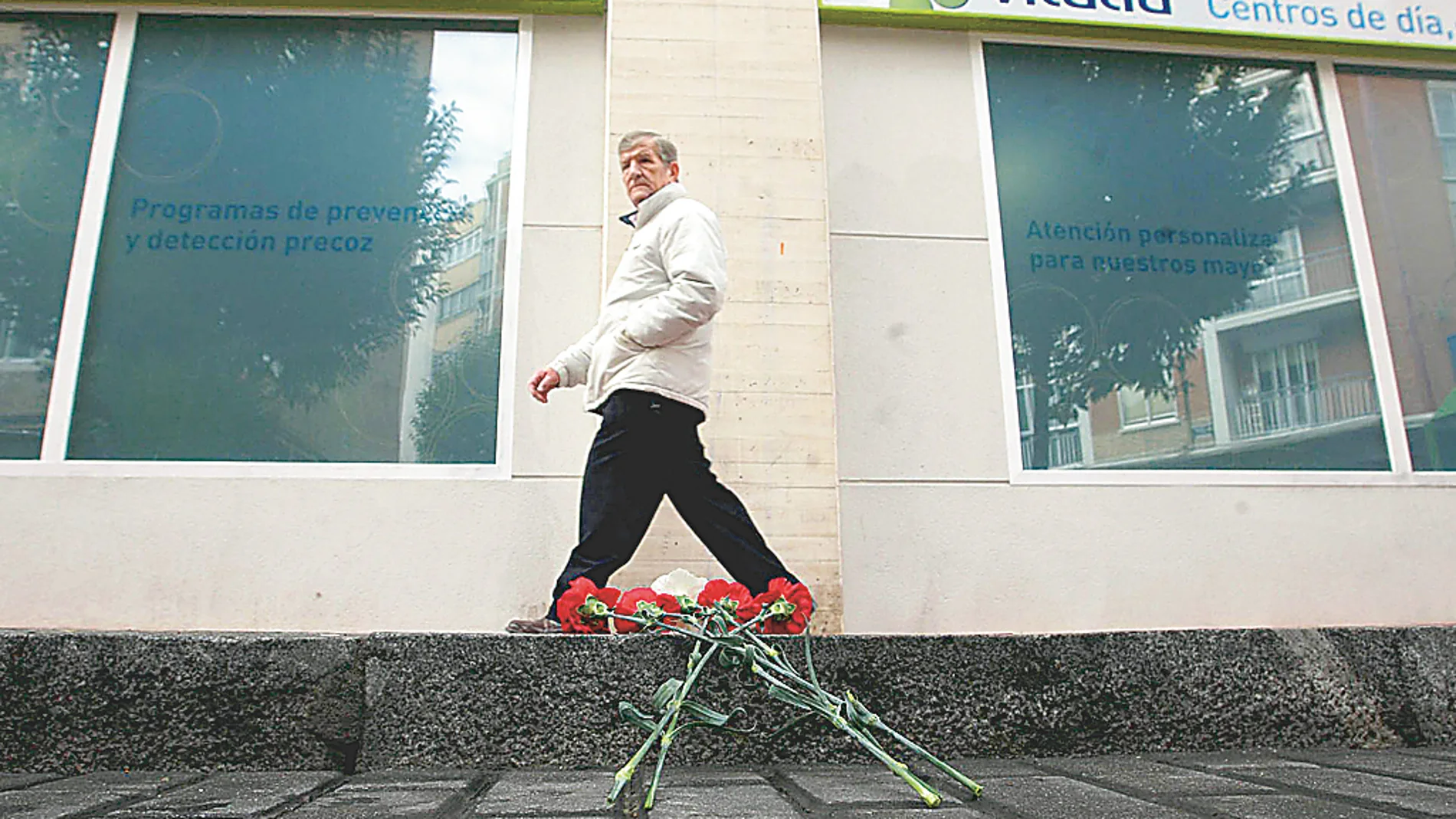 Un hombre pasa por delante de la acera donde se produjo el suceso, donde algunos vecinos depositaron claveles en memoria del fallecido