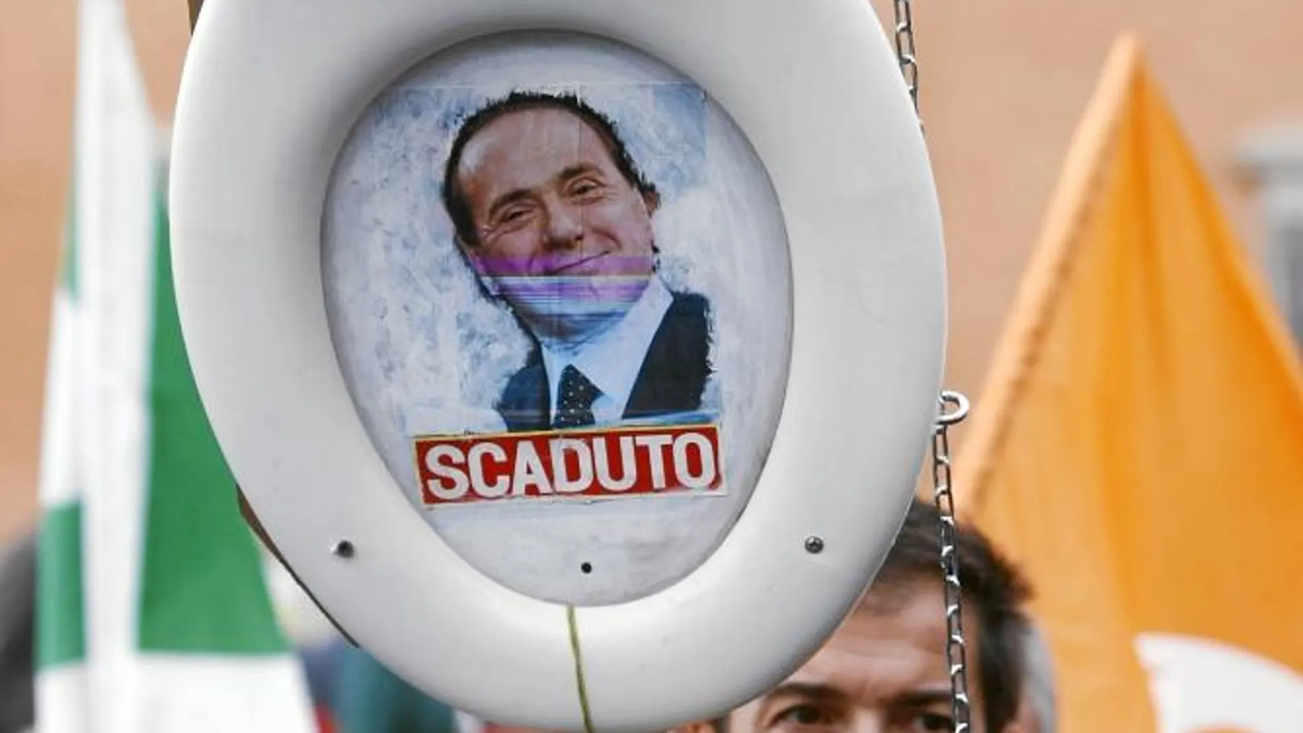 Un manifestante levanta una taza de váter con la imagen de Berlusconi en la que se puede leer «Caducado», en las protestas de ayer en Roma