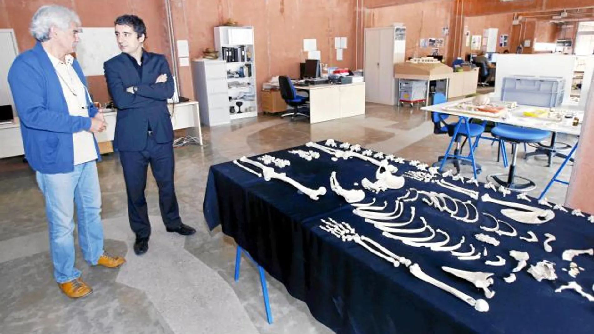 El consejero de Cultura, Pedro Alberto Cruz (d), y el director del yacimiento arqueológico de La Bastida, Vicente Llull (i), conversan ante el esqueleto de una mujer encontrado en una tumba intramuros