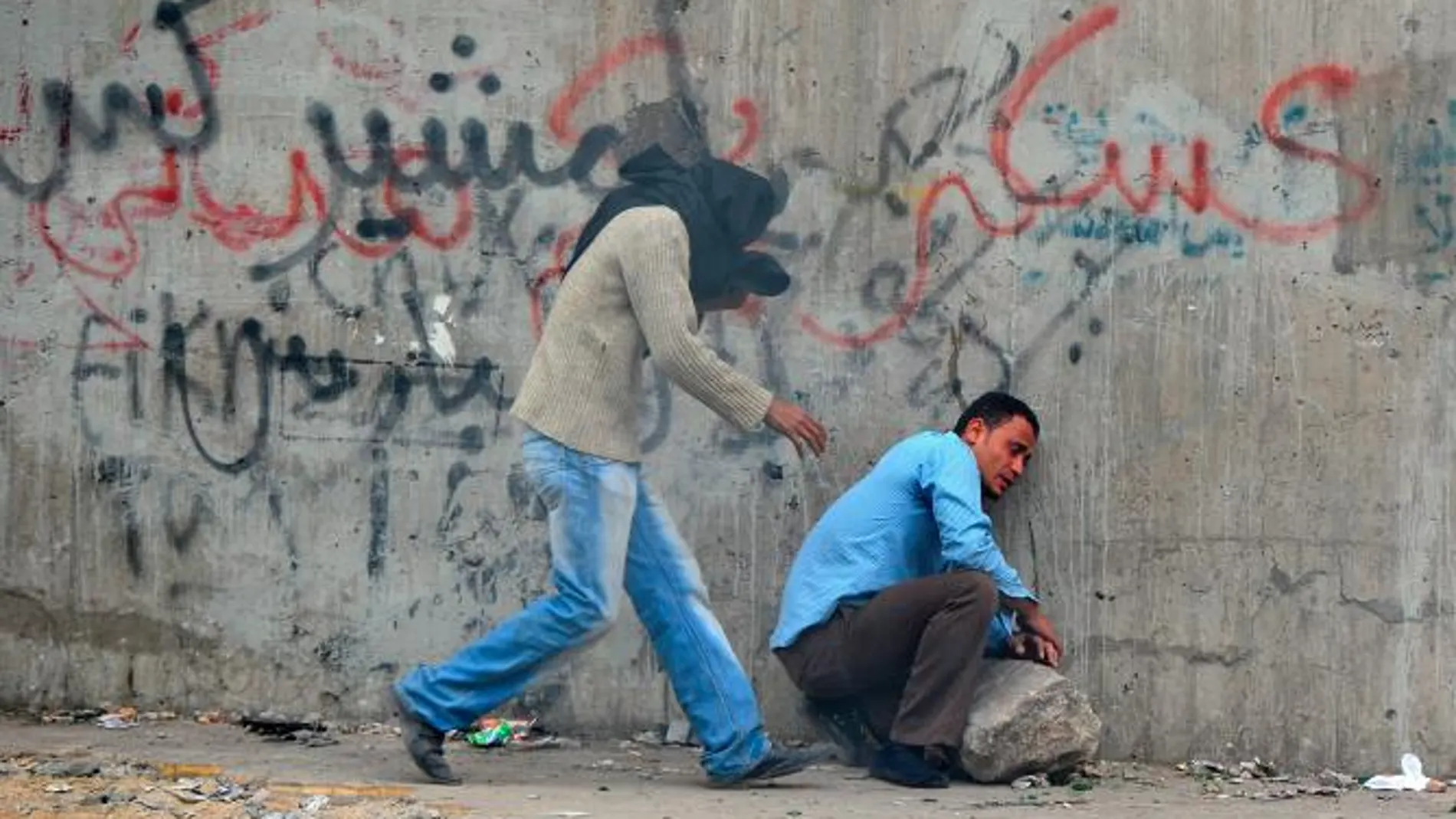 Un manifestante afectado por los gases lacrimógenos (d) recibe ayuda de otro durante los enfrentamientos con la policía y soldados en las proximidades de la Plaza Tahrir