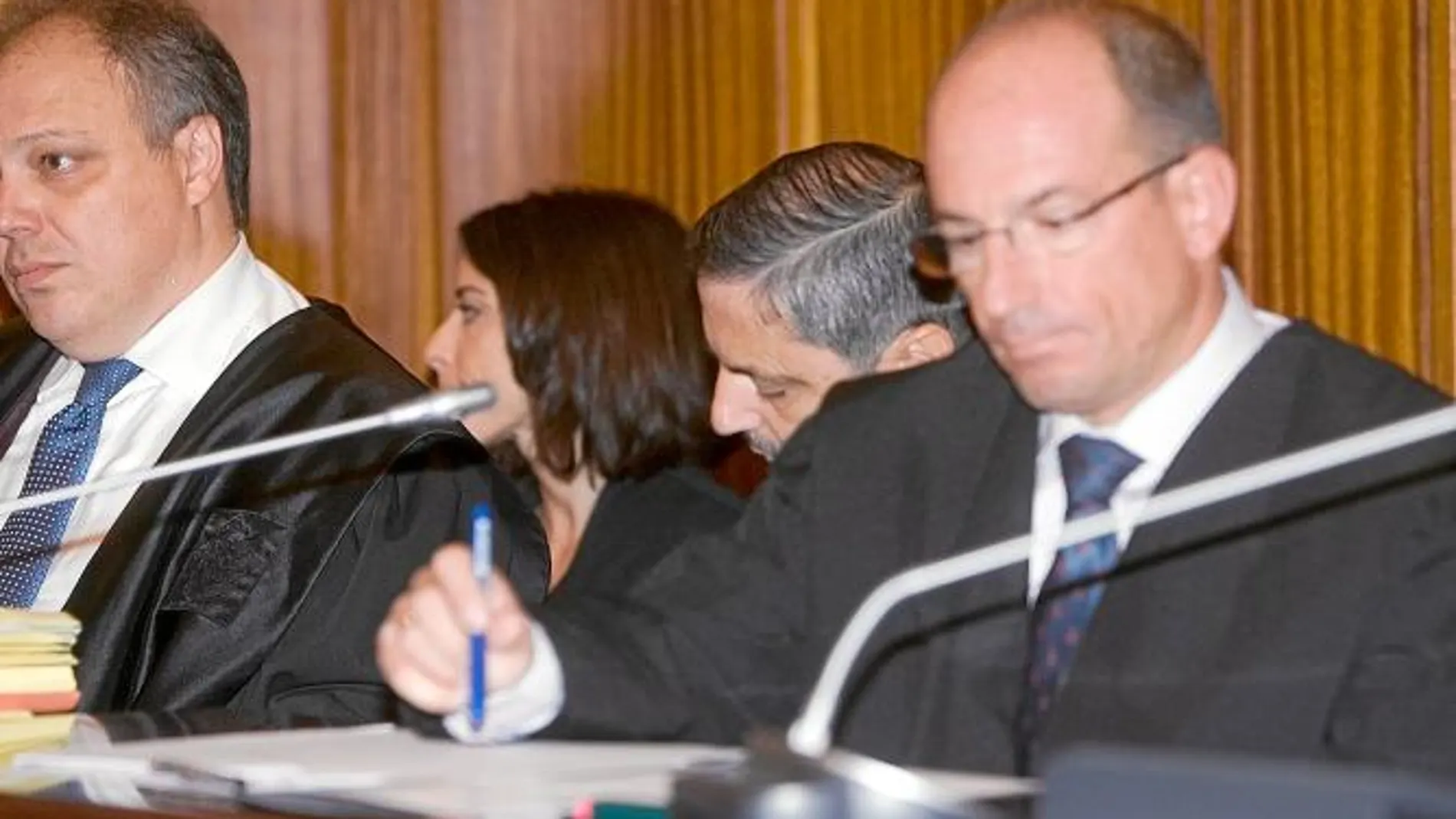 Fernando Mellet, en el centro, baja el rostro ante la presencia de las cámaras en la sala