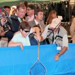El consejero de Fomento y Medio Ambiente, Antonio Silván, observa como pesca un niño en la Feria de Valladolid