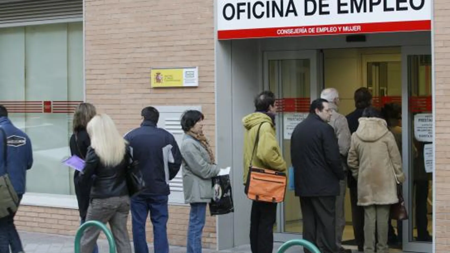 Un grupo de personas hacen cola en la entrada de una oficina de empleo