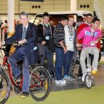 Un hombre y un grupo de jóvenes prueban en el Salón del Vehículo y Combustible Alternativos varios modelos de bicicletas eléctricas