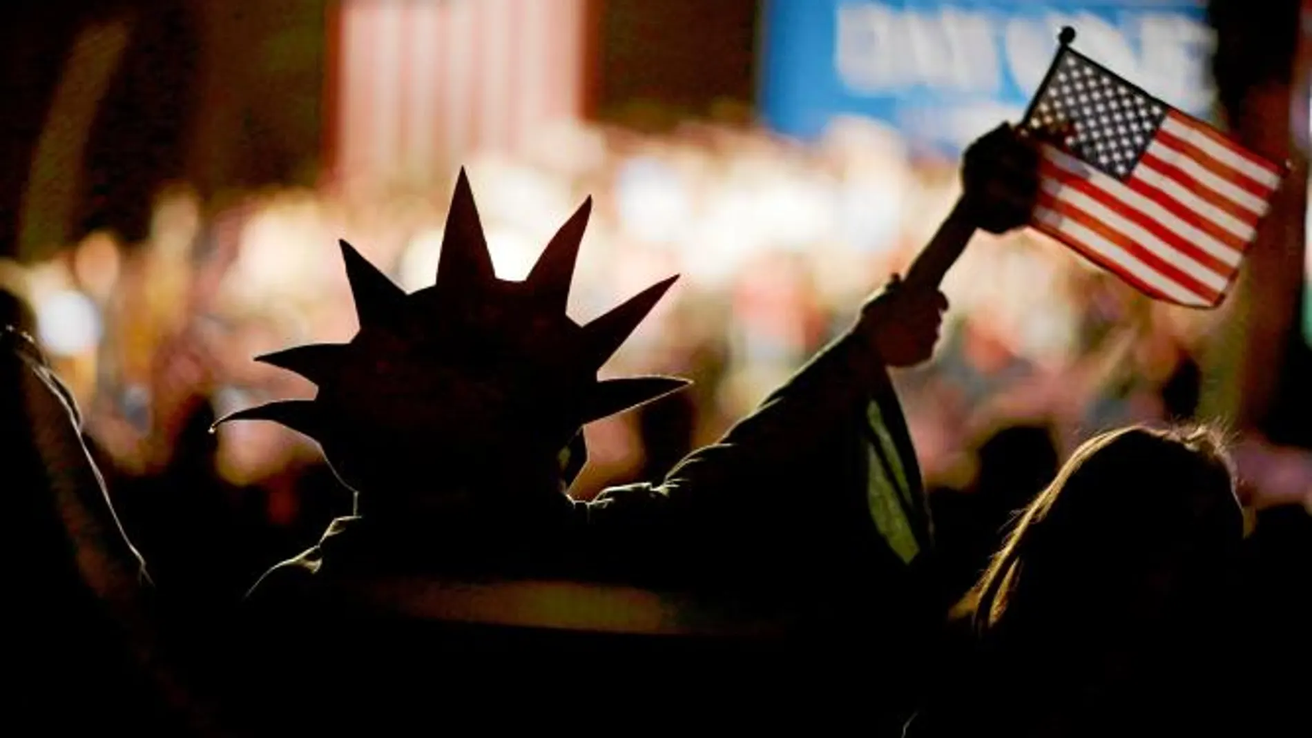 Una simpatizante de Romney, vestida como Estatua de la Libertad, ondea la bandera de EE UU en un acto de campaña en Colorado