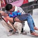VÍCTIMAS INDEFENSAS. Un hombre llora con el cadáver de su hijo, cerca de un hospital de Alepo, el pasado mes de octubre