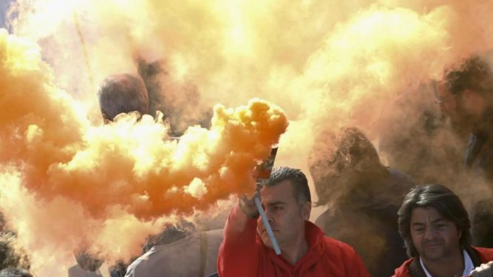Un manifestante agita una bomba de humo durante una protesta contra las medidas de austeridad en Nápoles