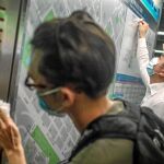Dos activistas limpian un tablón de avisos en la estación de metro de Sham Shui Po después de la masiva manifestación del domingo / Efe