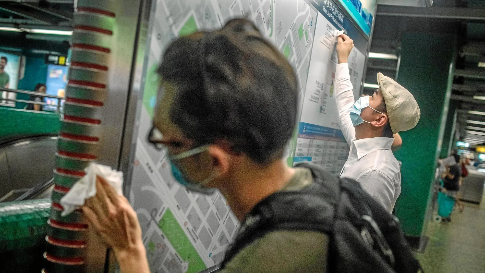 Dos activistas limpian un tablón de avisos en la estación de metro de Sham Shui Po después de la masiva manifestación del domingo / Efe