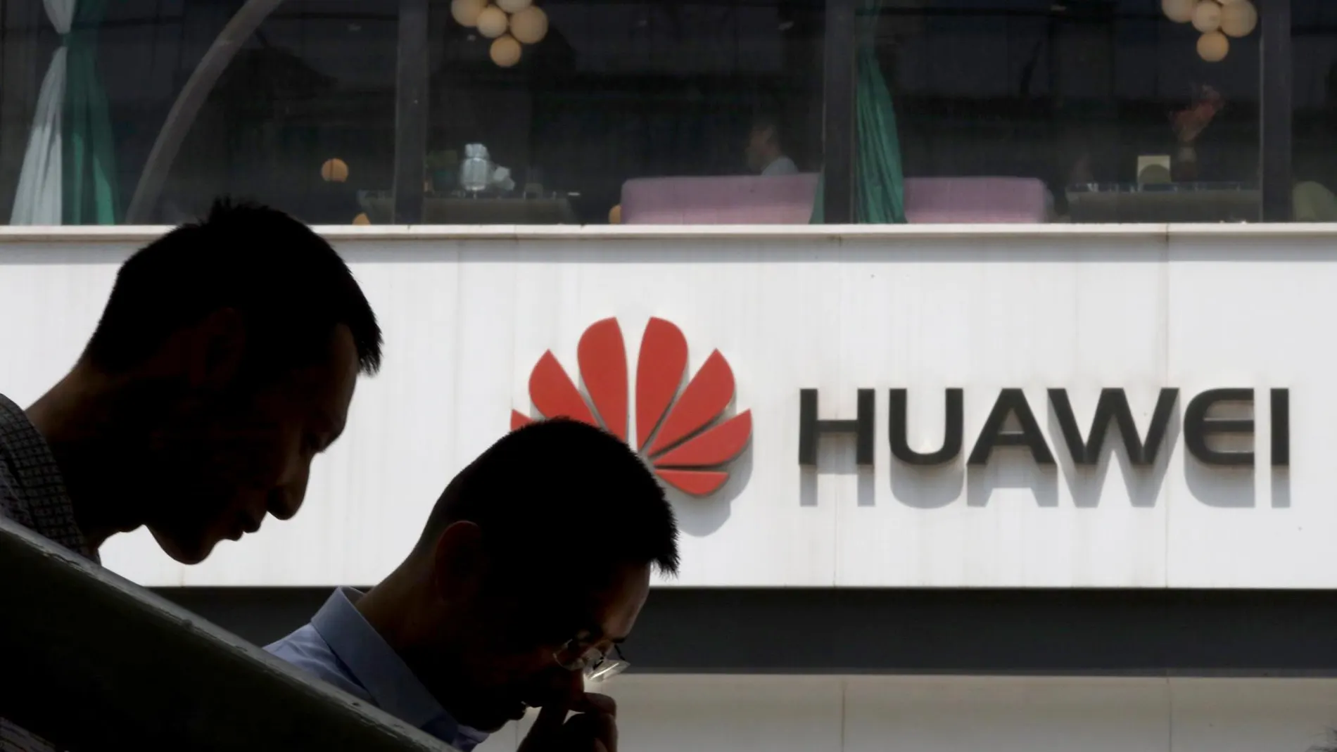 Dos jóvenes chinos con un logotipo de Huawei de fondo
